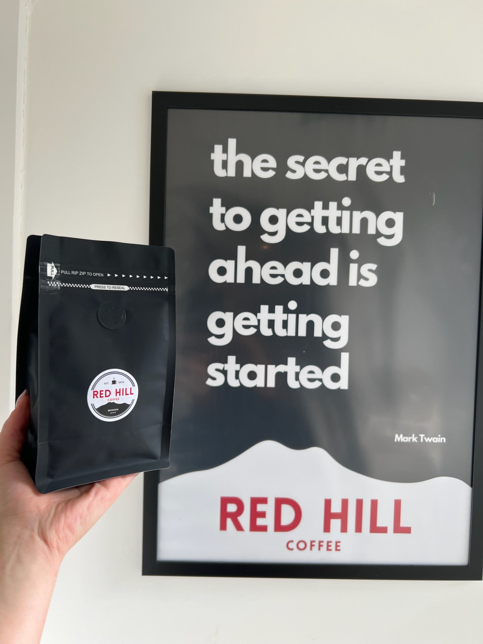 A bag of Red Hill House Blend held beside Red Hill artwork