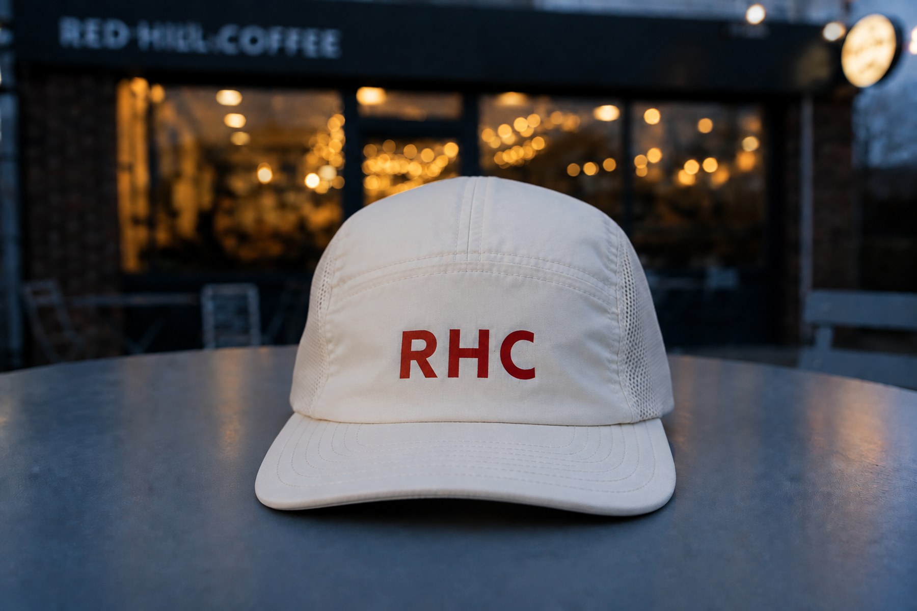 Ecru Red Hill Active Cap with red RHC lettering outside Red Hill Coffee