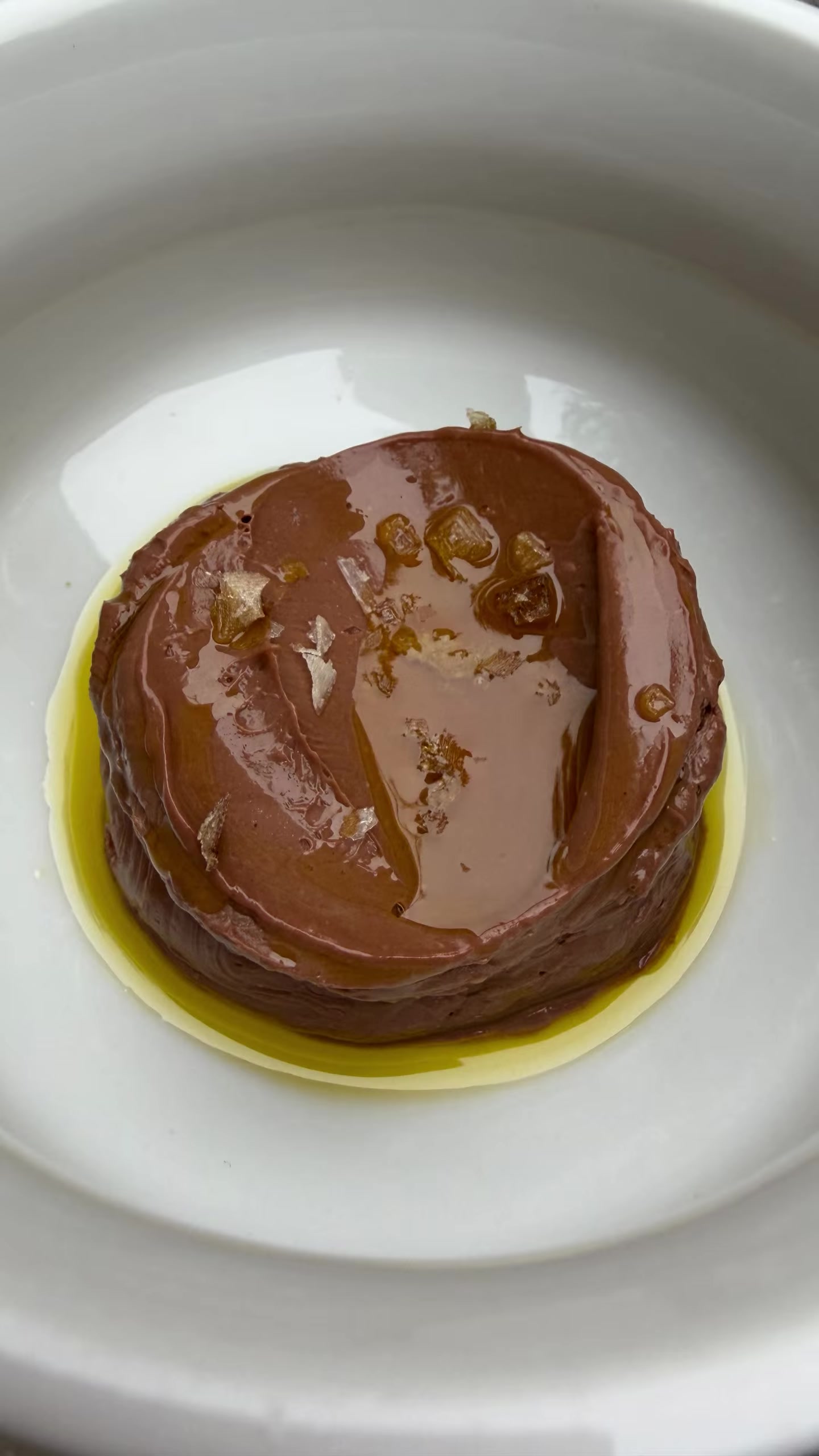 A glossy round dessert served on a white plate